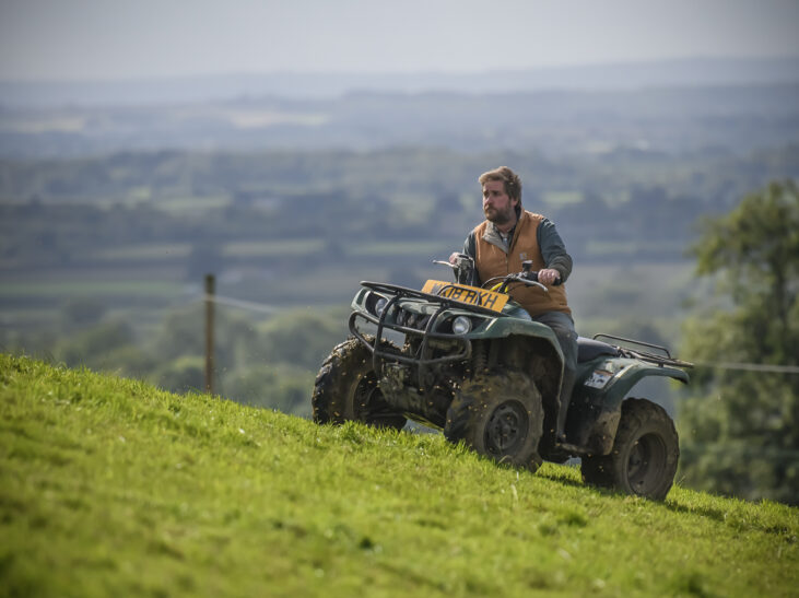 Farmer riding quad bike on hill side