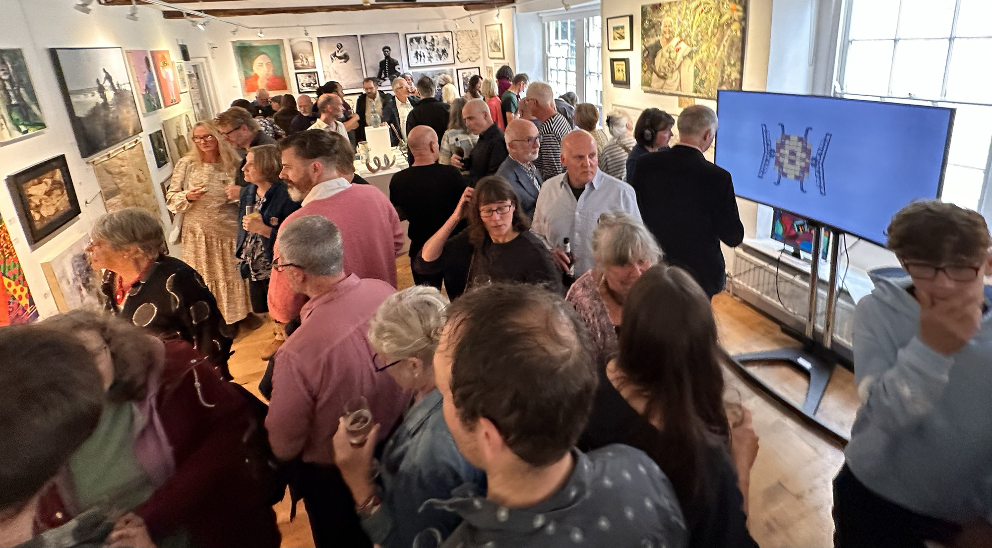 Gallery space full of people looking at artwork on display